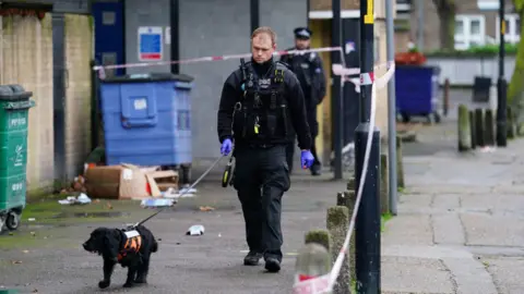 PA Media A police sniffer dog works at the scene outside Spenlow House