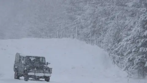 REUTERS/Russell Cheyne A Land Rover drives on a snow-covered road near Trinafour, Scotland.