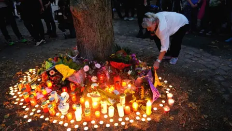 EPA A woman lights a candle after a mourning march for a 22-year-old man killed in Köthen, Germany, 9 September 2018