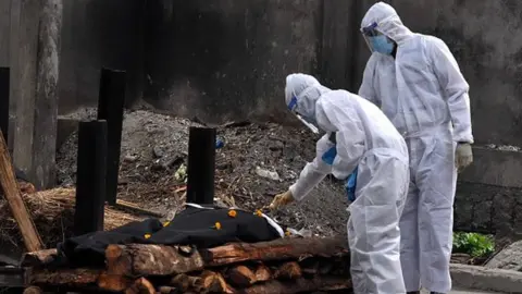 Getty Images Relatives performing last rites, who died from Covid at a crematorium in Guwahati, India.