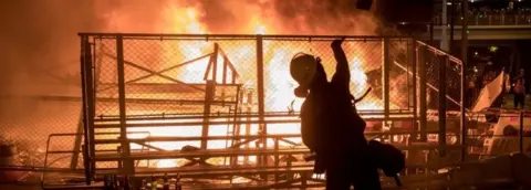 Getty Images A protester throws a bottle onto a burning barricade in Hong Kong. Photo: 31 August 2019