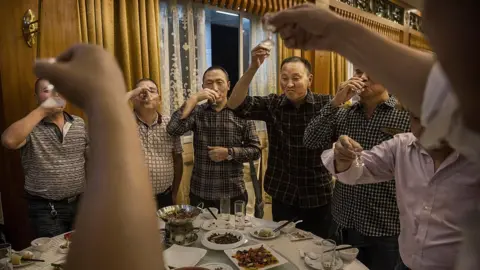 Getty Images Chinese men toast each other and drink Moutai, the most famous wine called baijiu