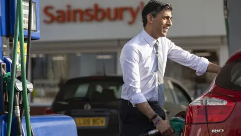 SIMON WALKER  HM TREASURY Rishi Sunak fills up car at forecourt