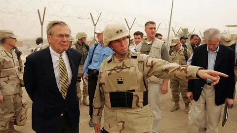 Getty Images Secretary of Defense Donald Rumsfeld (L) is briefed about detainee operations by Major General Geoffry Miller (2nd L), the Deputy Director of Detainee Operations for Iraq while touring the Abu Ghraib Prison Facility May 13, 2004 outside Baghdad, Iraq