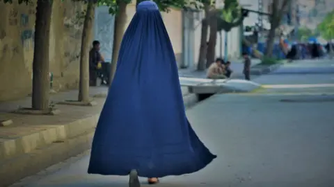 Getty Images A woman walks down the street in Kabul in May 2022 (file picture)