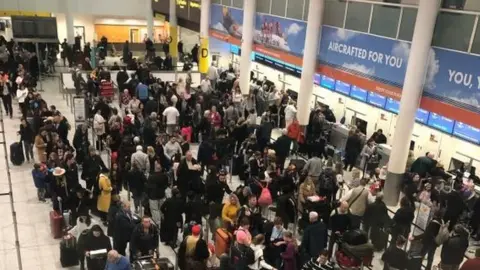 PA Passengers queue at Gatwick