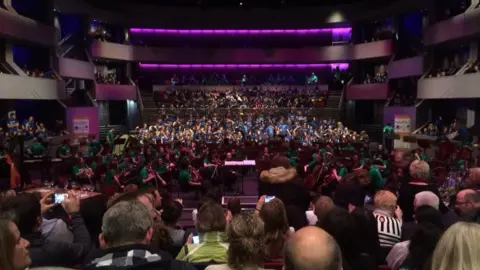 Martin Heath/BBC Hundreds of children performing on stage in front of a full audience at the Derngate Theatre