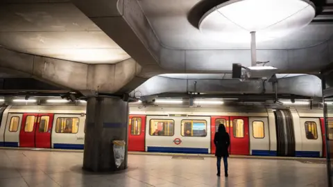 Getty Images Woman stands at empty Tube station