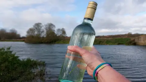 We Swim Wild a swimmer brandishes a wine bottle full of water