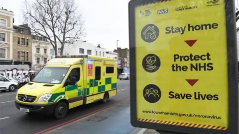 EPA An ambulance passes a coronavirus poster in east London