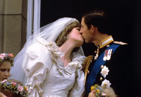 PA The newly married Prince and Princess of Wales kiss on the balcony of Buckingham Palace after their wedding ceremony at St. Paul's cathedral.