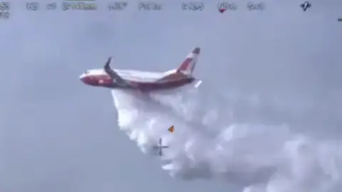 NSW RURAL FIRE SERVICE The Coulson Aviation 737 Fireliner Airtanker drops water over a bushfire in New South Wales