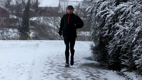 Getty Images A runner braves freezing conditions in a park in Blackwood, Wales