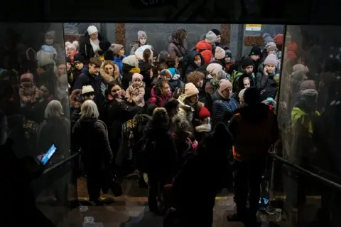 BBC Women and children queue at Lviv station for a train to Poland. Tens of thousands are passing through the station every day