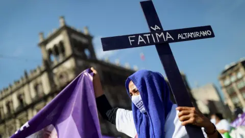 Reuters A woman holds a cross as relatives and friends of victims of femicide take part in a march in Mexico City