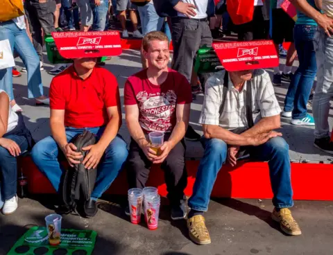 Peter Dench Football fans with makeshift sunshades