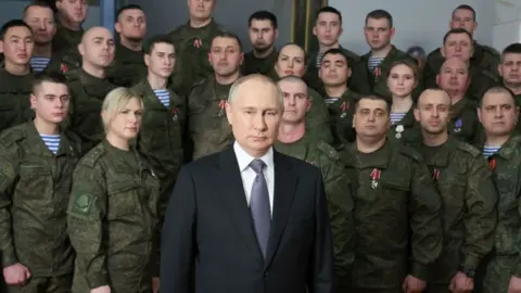 Getty Images President Putin surrounded by people in uniform during his New Year's address