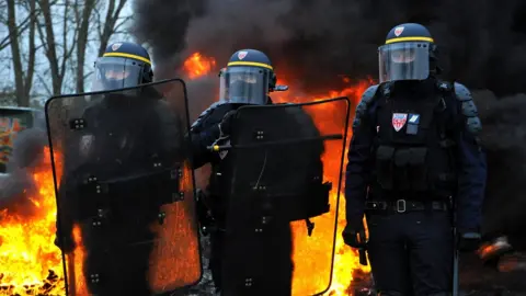 Getty Images Riot police stand near a fire during a demonstration against rising fuel and oil prices in Crespin, northern France