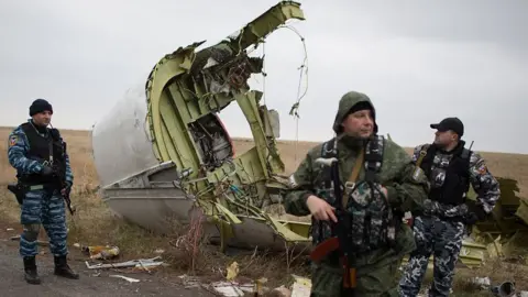 Getty Images Pro-Russian gunmen stand guard as Dutch investigators (unseen) arrive near parts of the Malaysia Airlines Flight MH17 at the crash site near the Grabove village in eastern Ukraine on November 11, 2014