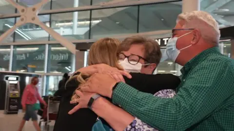 Naomi Hooper hugging her parents at Heathrow