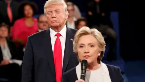 Reuters Donald Trump listens as Hillary Clinton answers a question during presidential debate at Washington University in St Louis, Missouri, U.S., October 9, 2016