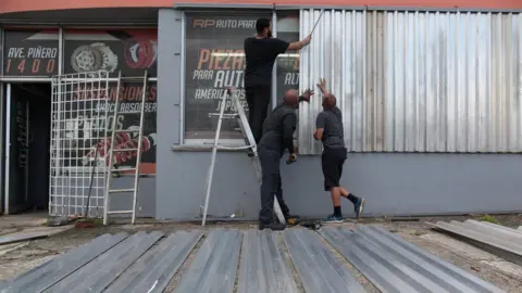 Reuters Men cover the windows of a car parts store in preparation for Hurricane Irma in San Juan