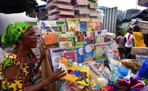 AFP A woman sells second-hand books and magazines at a roadside bookshop in Ivory Coast"s largest city Abidjan on September 19, 2018.