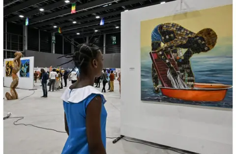 Issouf Sanogo/AFP Young woman looking at a piece of art.
