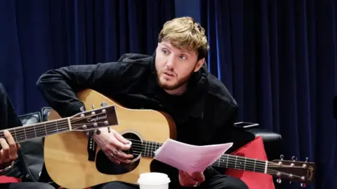 Sarah Jeynes/BBC James Arthur playing a guitar