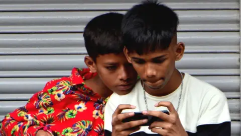 Getty Images Children watch a mobile screen in Mumbai, India.