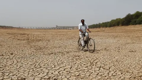 Getty Images An Indian cyclist rides along dry bed of Sabarmati river near the Sant Sarovar, a reservoir situated in Gujarat's capital Gandhinagar, some 30 Kms. from Ahmedabad on May 1, 2019.