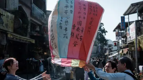 Getty Images People fly a lantern in New Taipei, bearing their wishes for peace on the island