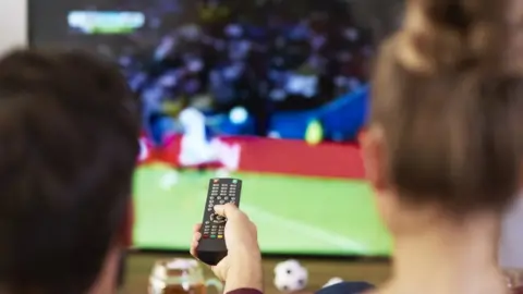 Getty Images couple watch football on tv - stock image