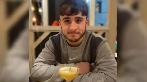 Family photo Owen Dunn looking at the camera with a drink in front of him