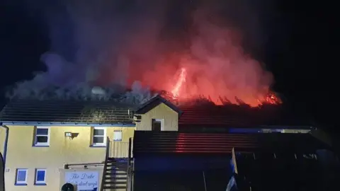 Mid and West Wales Fire and Rescue Service Flames burn through the roof of the Duke of Edinburgh pub in Newgale, Pembrokeshire