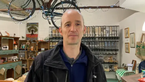 BBC Customer Ian Humble at Roots cafe with food dispensers behind him