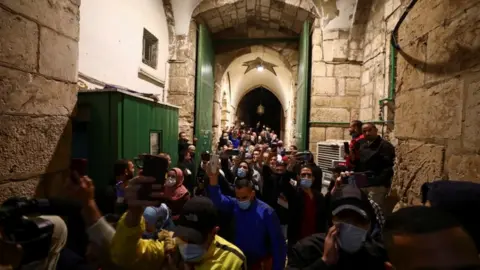 Reuters Worshippers, some wearing masks, hold up their mobile phones while entering the compound housing the Al-Aqsa Mosque