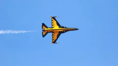 Yellow and black military plane in the sky, tilted vertically