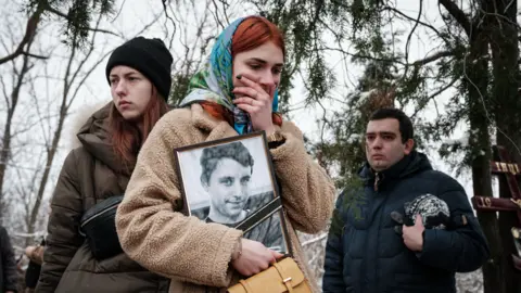 Getty Images Mourners at the funeral of a Ukrainian serviceman in Ukraine