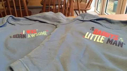 Ben Kendall/PA Two baby bodysuits with misspelt slogans