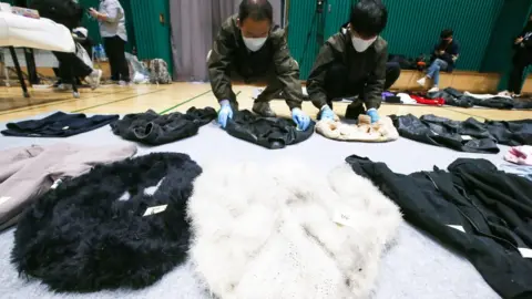 EPA Police officers check clothes collected from the scene of an stampede, at a multi-purpose gym in Seoul, South Korea,