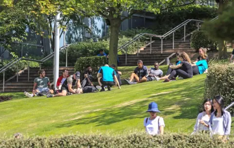 PA People enjoy the sunshine at Chavasse Park in Liverpool