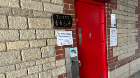 Chippenham Town Council A public toilet block with a red door.