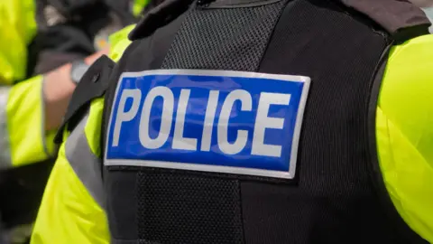 A police officer's jacket up close. The word police is written on the back. 