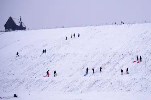 AFP People sledge down a hillside at Butterley Reservoir in Marsden, West Yorkshire, on 14 January 2021