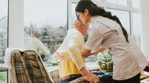 Getty Images/Catherine Falls Commercial A care worker helps elderly patient (stock photo)