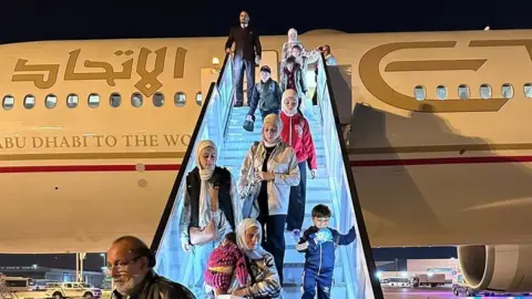 BBC Palestinians disembark an evacuation flight that has taken them from Egypt to the UAE