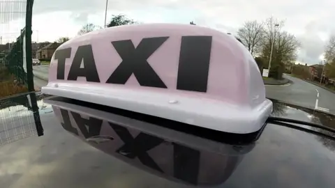 BBC General view of a TAXI sign on the roof of a licensed mini cab.