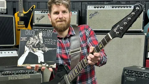 Gardiner Houlgate auctioneers Auctioneer Luke Hobbs with Chuck Berry's 1964 Gibson Firebird V guitar