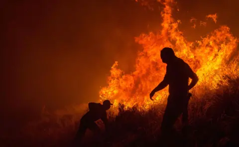 EPA The silhouettes of two men fighting a fire in Cape Town, South Africa - Sunday 27 January 2019